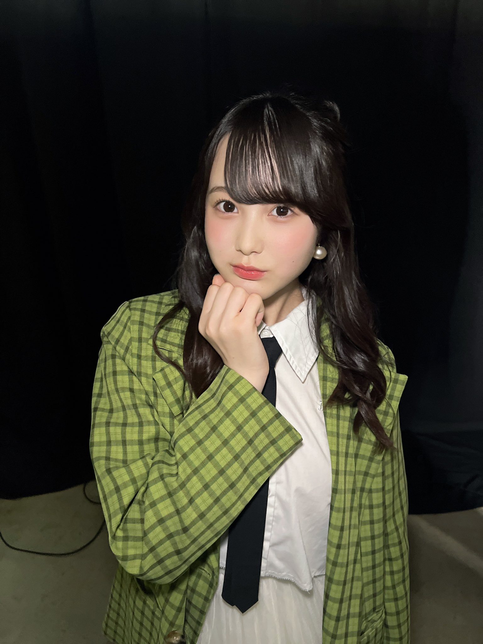 真顔の本田紗来が右手をグーにして顎に当てている