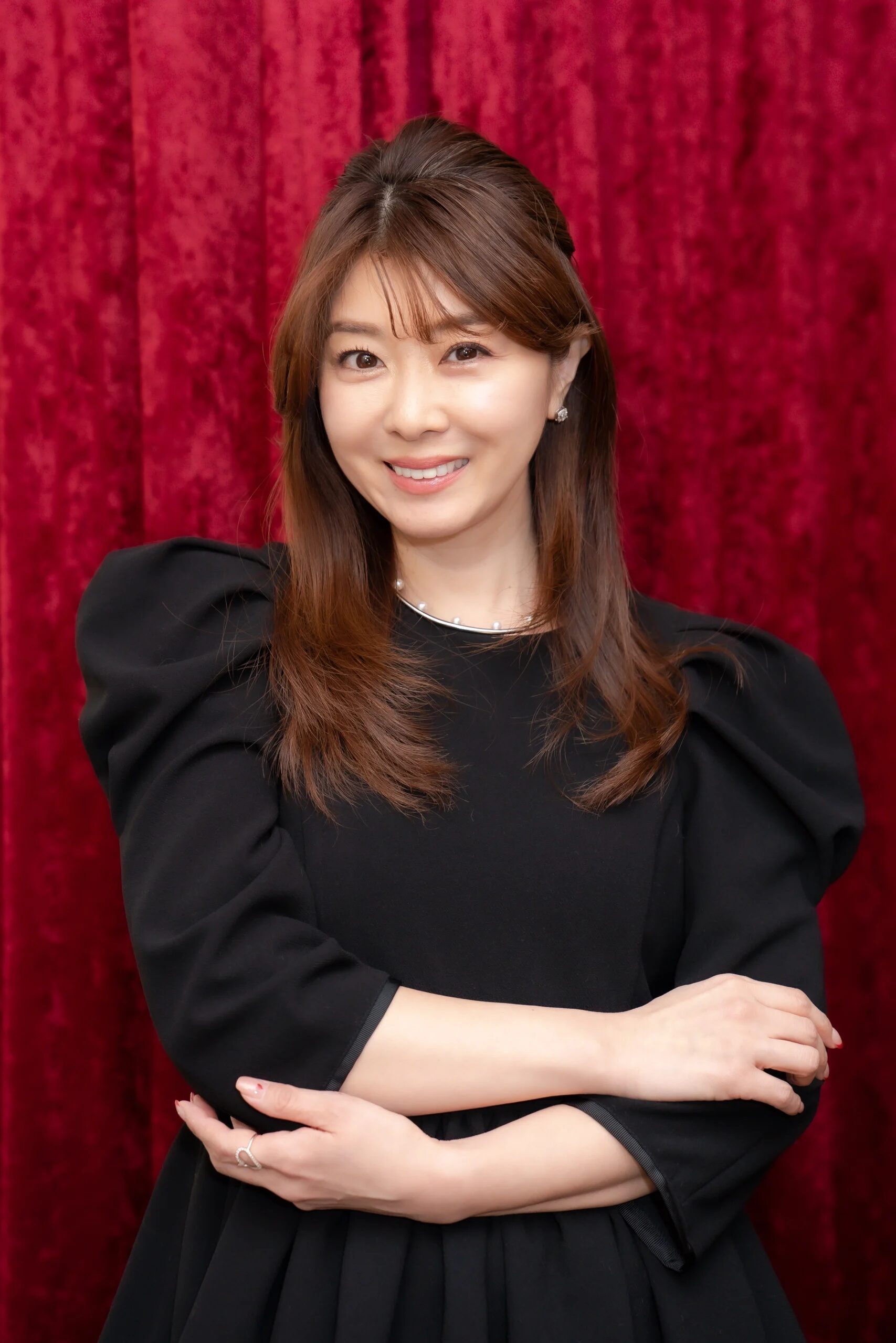 笑顔の矢部美穂が軽く腕を組んでいる