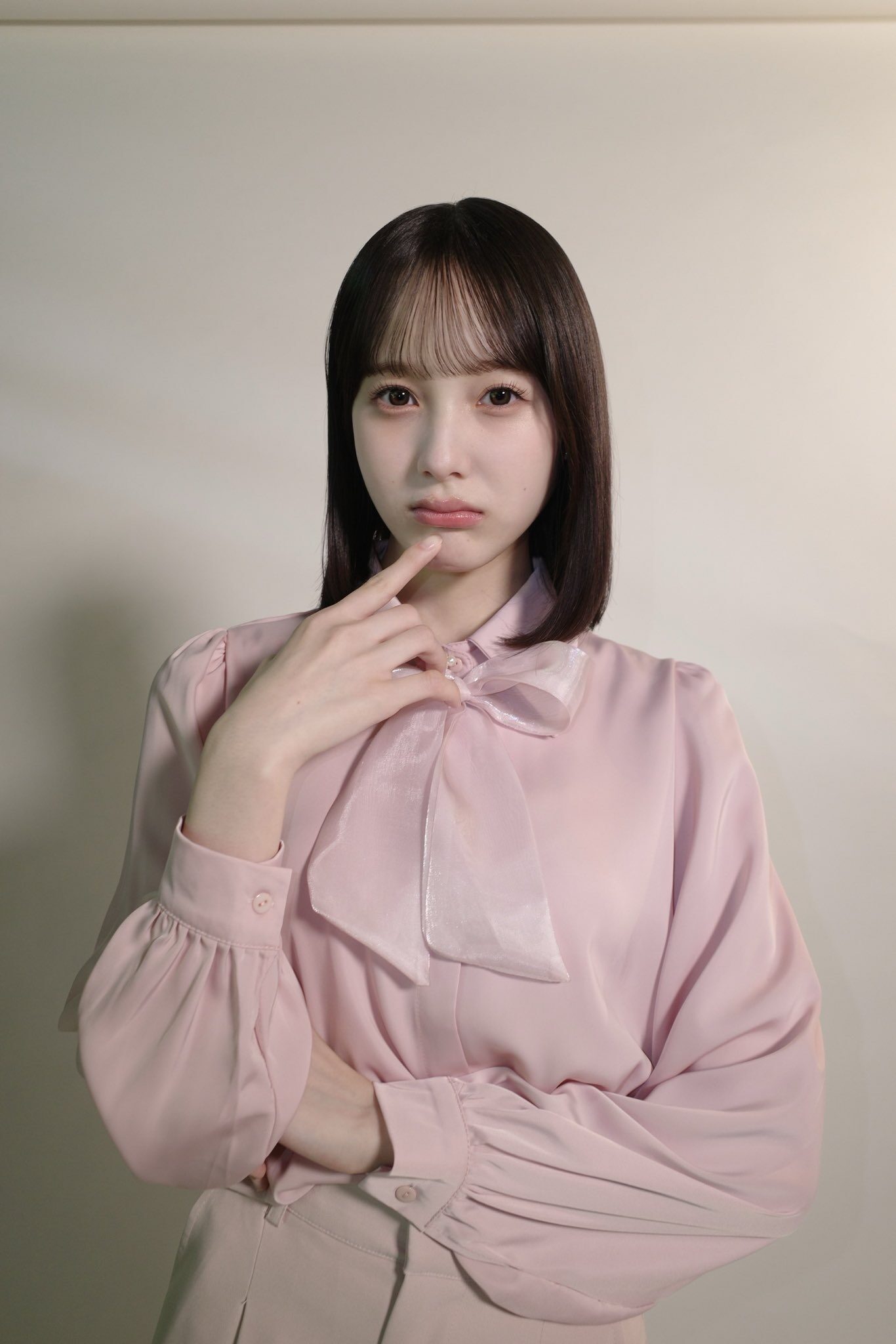 真顔の本田紗来が顎に右人差し指を当てている