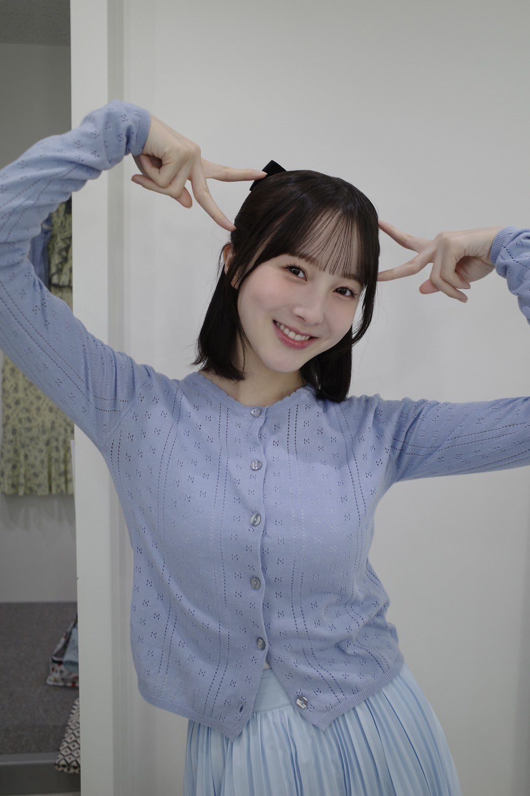 笑顔の本田紗来が両手でピースして頭にその指をつけている