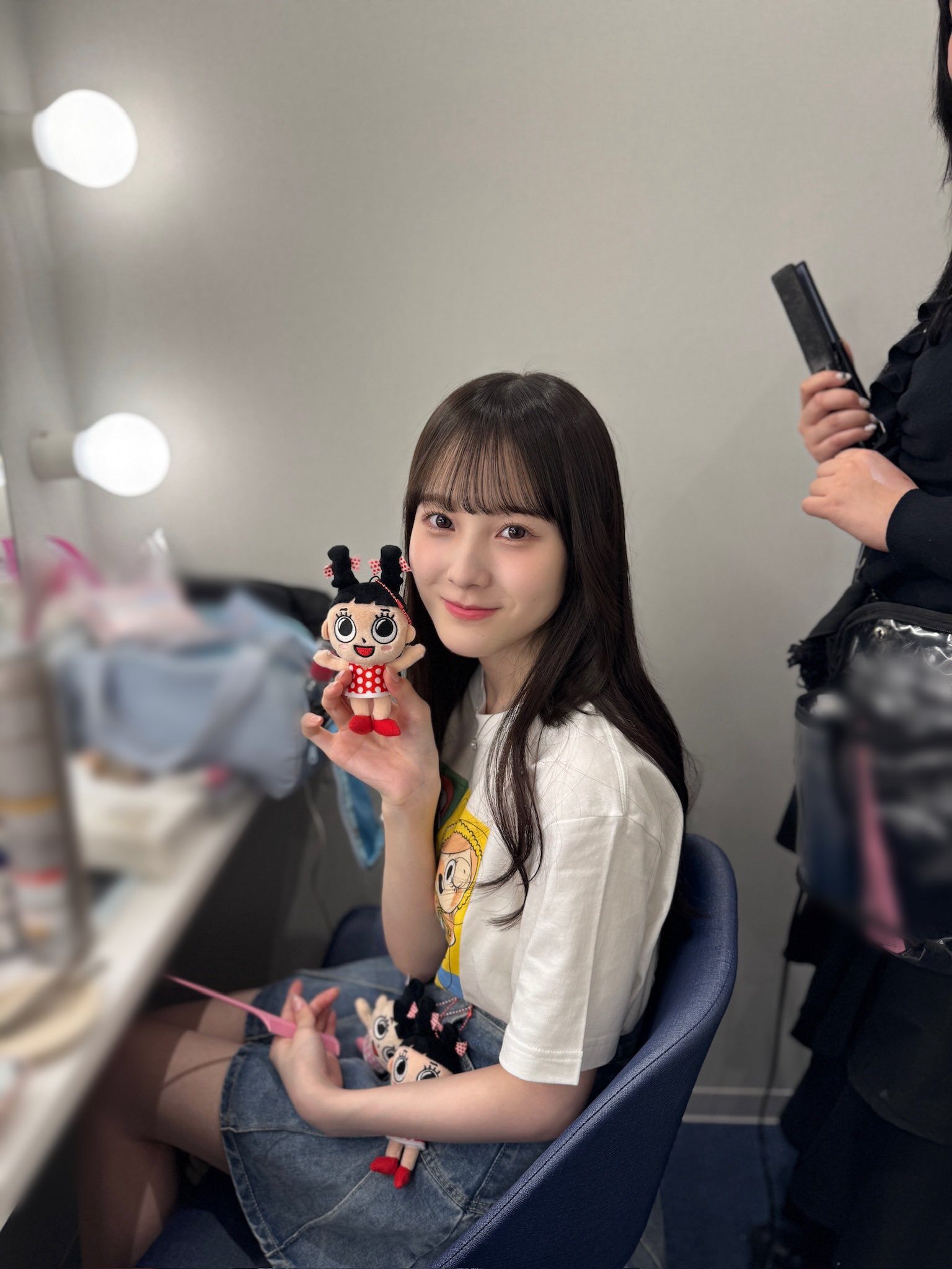 ちいさなマスコットぬいぐるみを右手で持ってこちらに見せている本田紗来