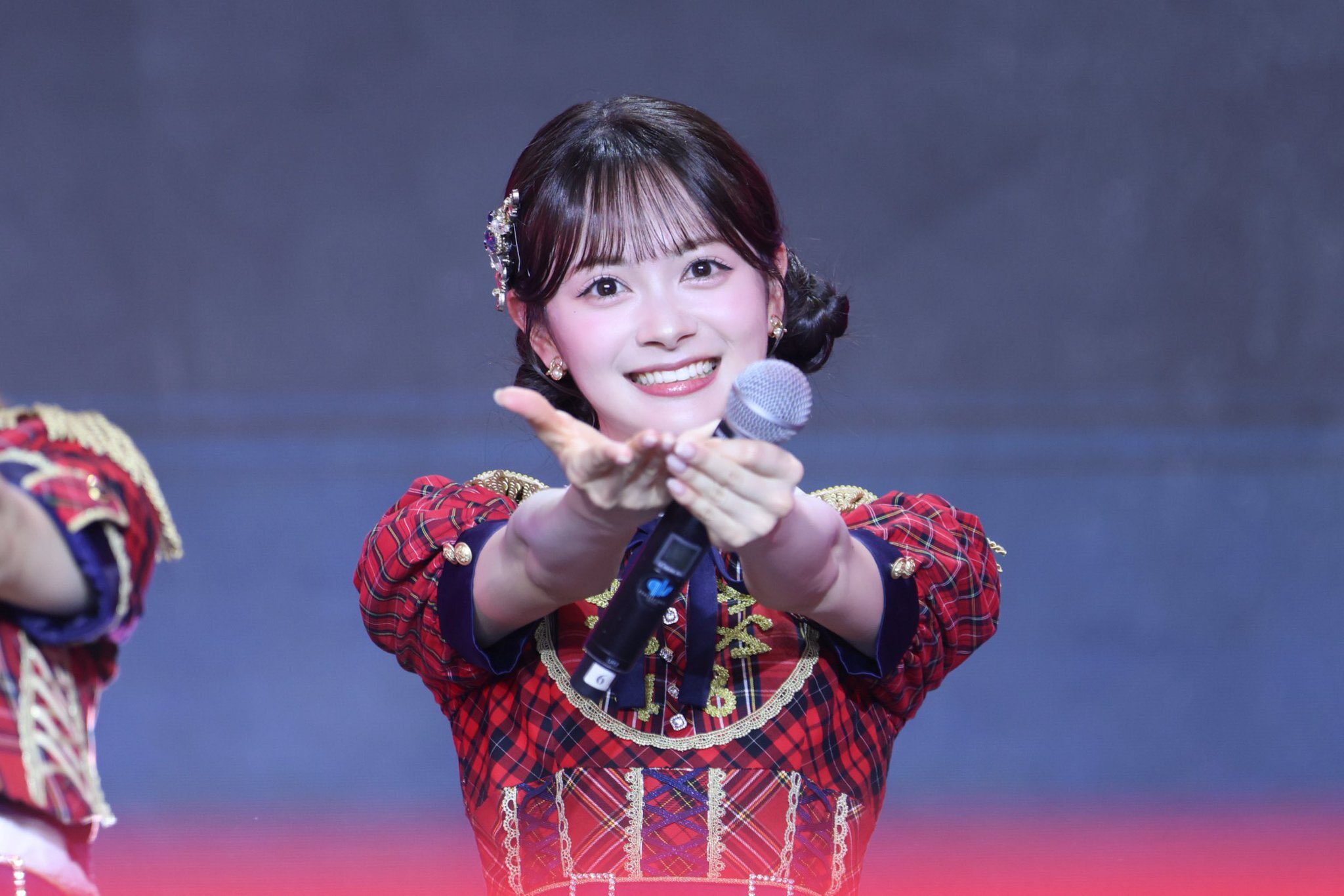 コンサートで伊藤百花が左手でマイクを持ったまま両手を差し出している