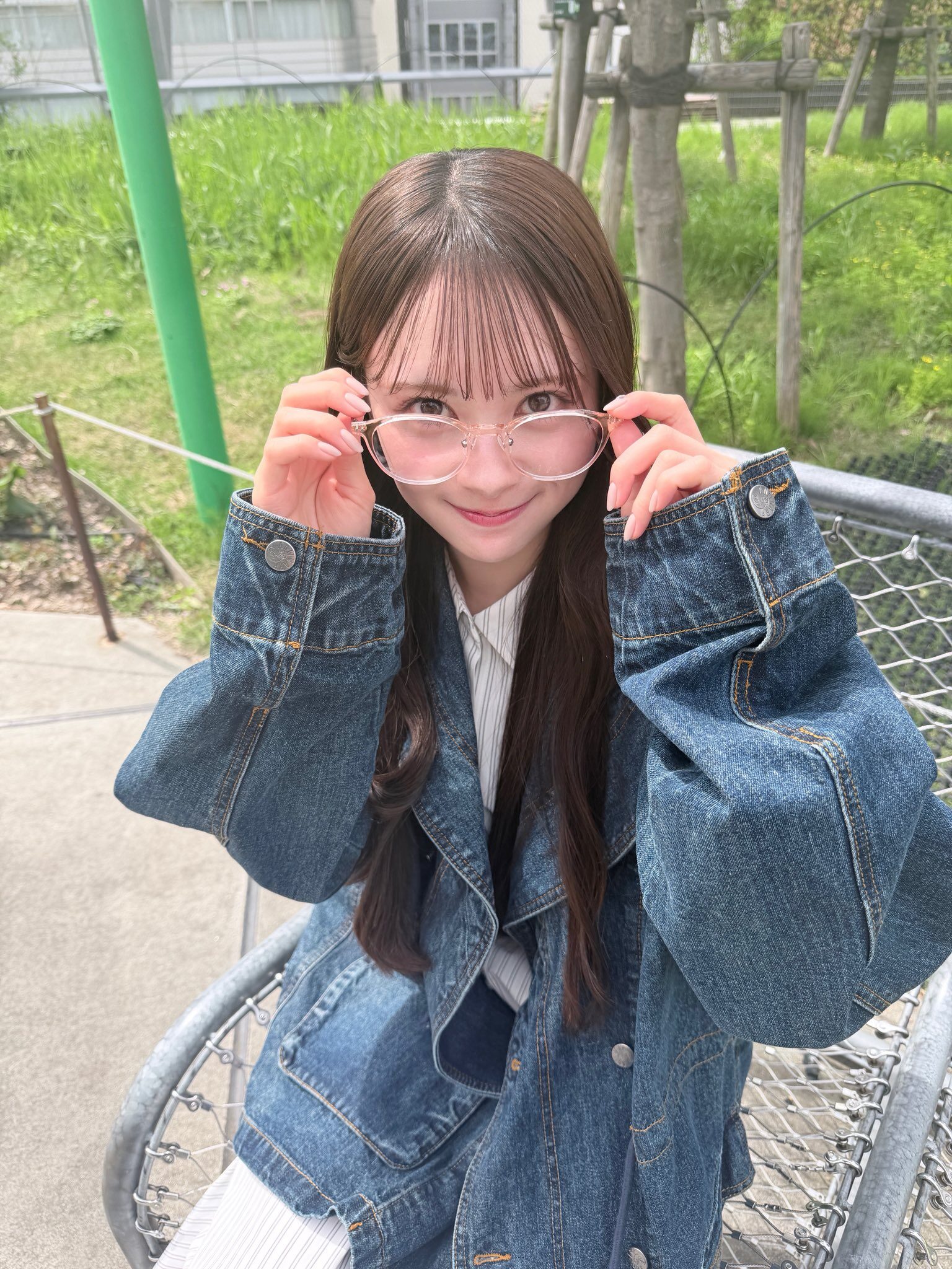 笑顔の伊藤百花が薄いピンクのメガネを掛けようとしている